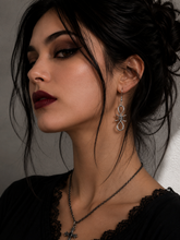 Midnight Grunge 5-Pair Silver Gothic Earring Set on a marble tray, featuring textured snake hoops, sword dangles, skull butterflies, spiders, and witch knot earrings by Marjan Collections