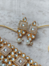 Gold and pearl jewelry set on a textured surface