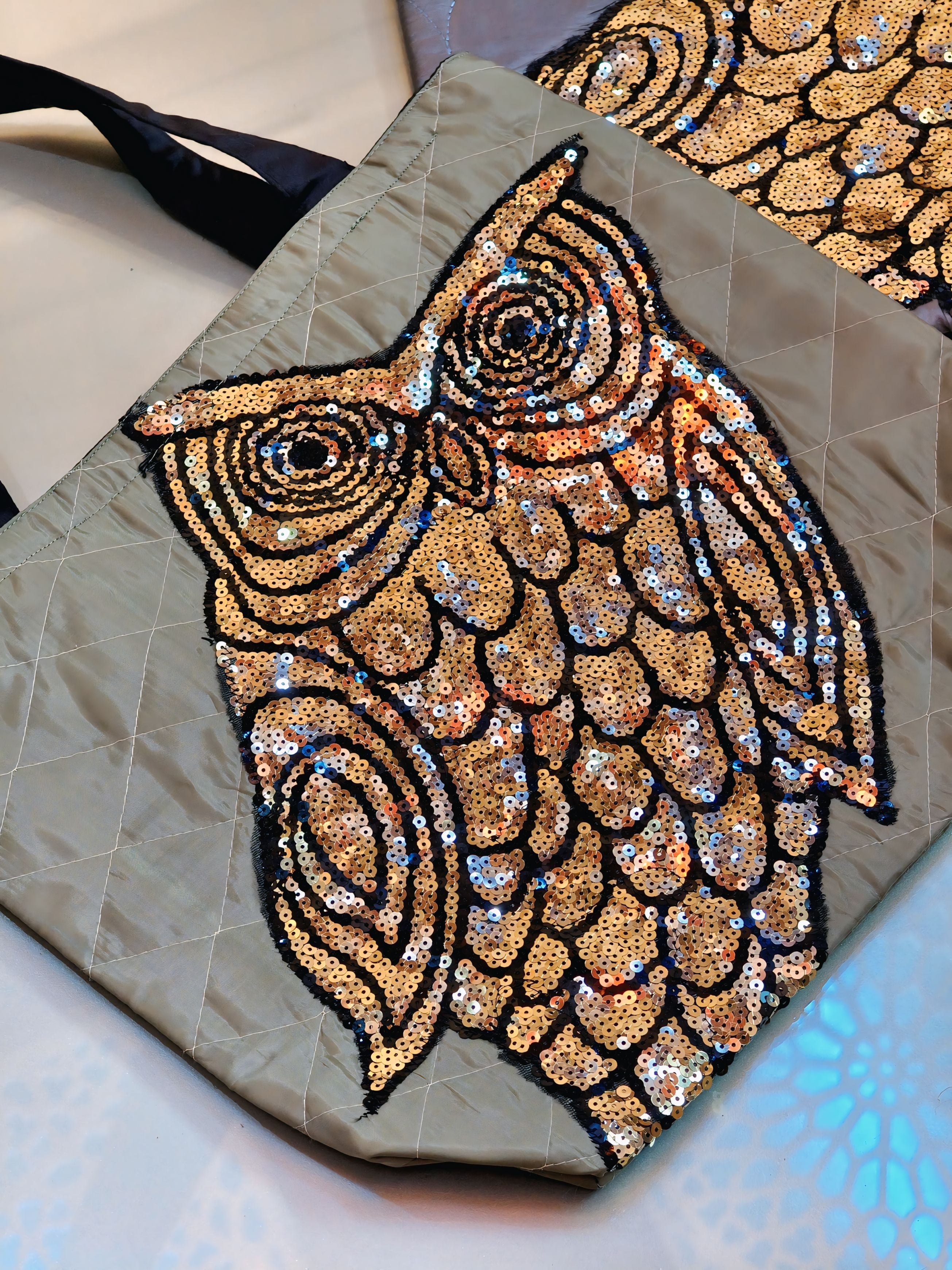 Sequined owl design on a textured surface