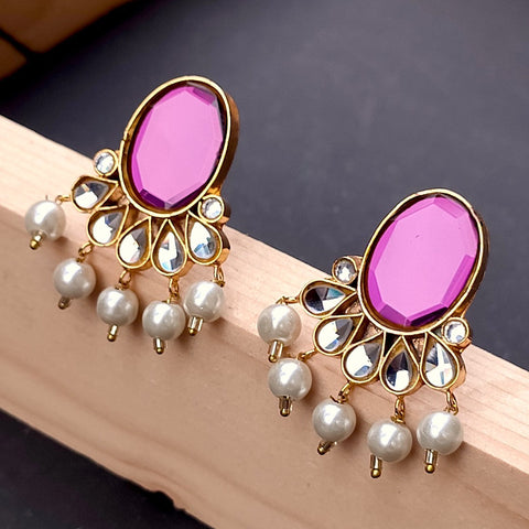 Pair of earrings with purple gemstones and pearl drops on a wooden surface.