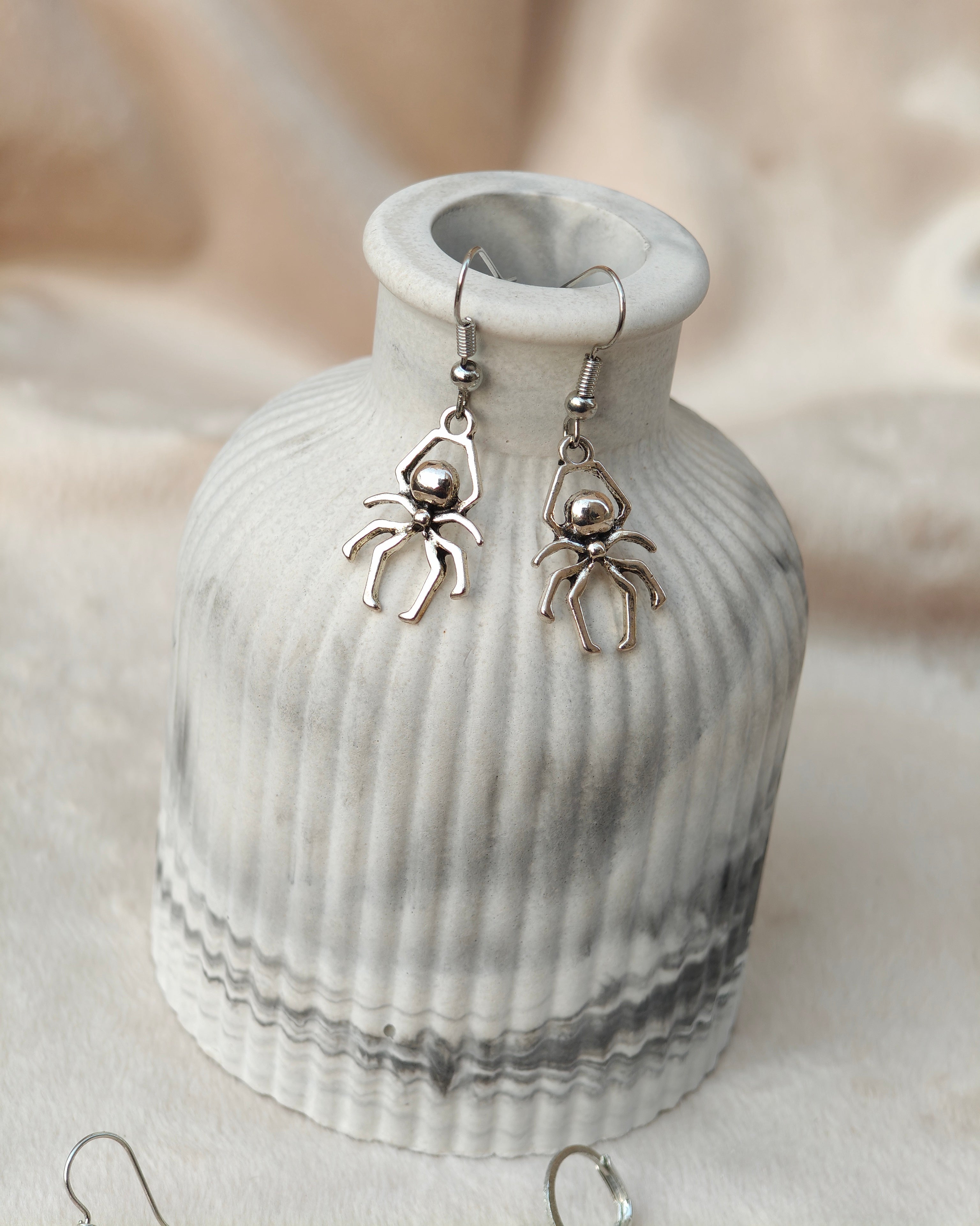 Midnight Grunge 5-Pair Silver Gothic Earring Set on a marble tray, featuring textured snake hoops, sword dangles, skull butterflies, spiders, and witch knot earrings by Marjan Collections