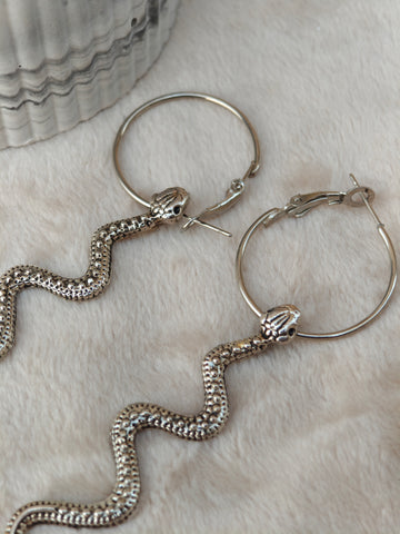 Midnight Grunge 5-Pair Silver Gothic Earring Set on a marble tray, featuring textured snake hoops, sword dangles, skull butterflies, spiders, and witch knot earrings by Marjan Collections