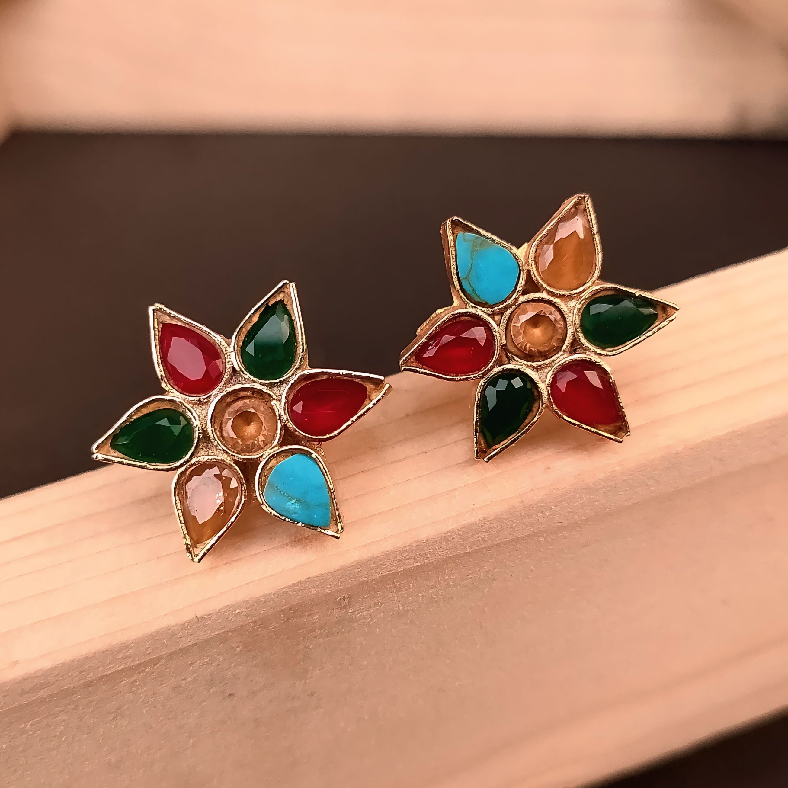 Colorful flower-shaped earrings on a wooden surface