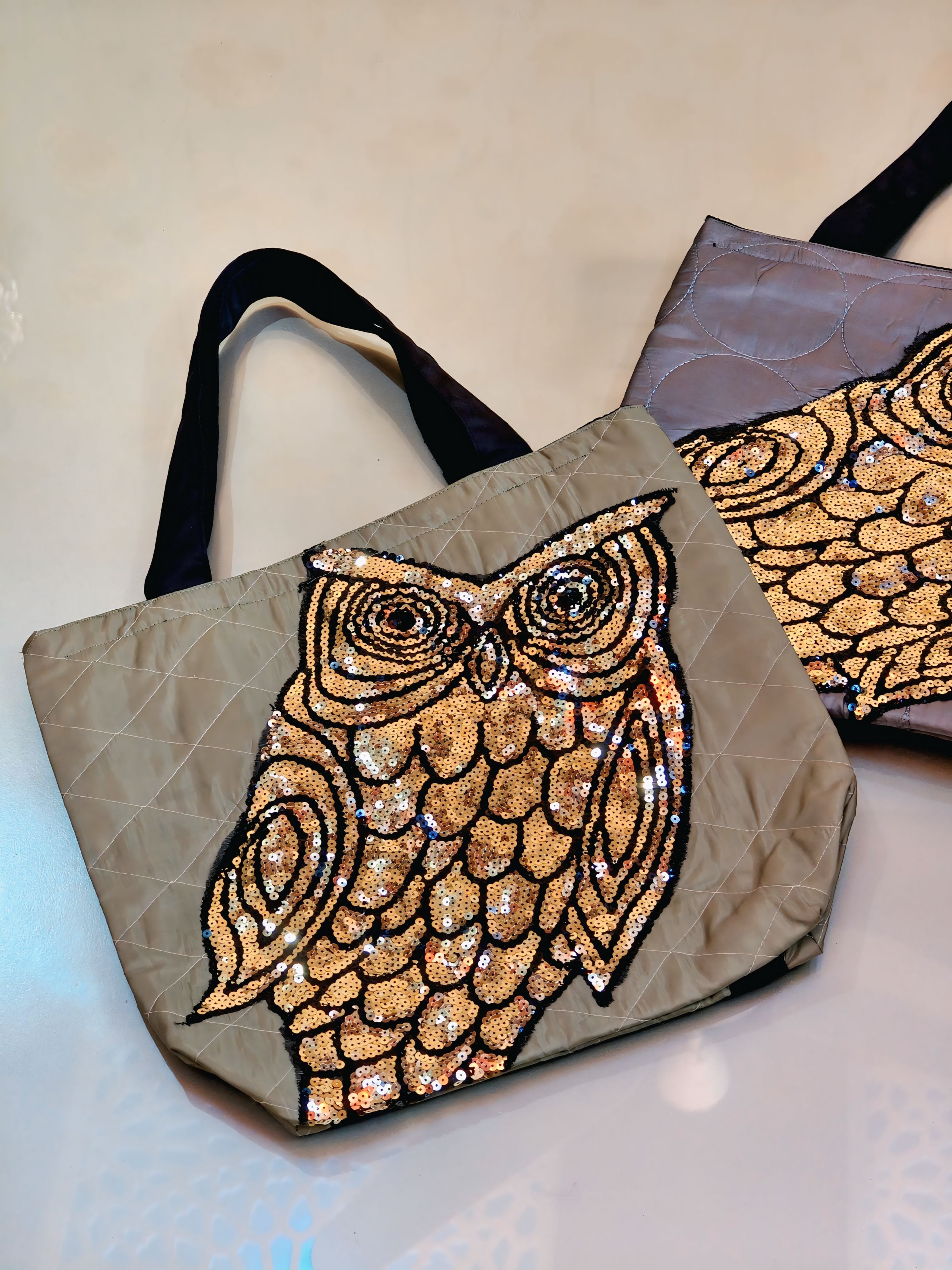 Tote bag with gold owl design on a beige background