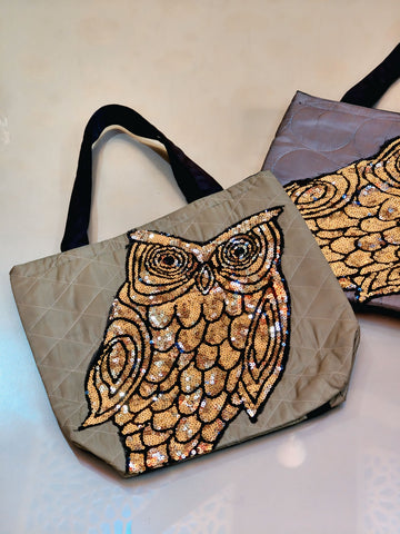 Tote bag with gold owl design on a beige background