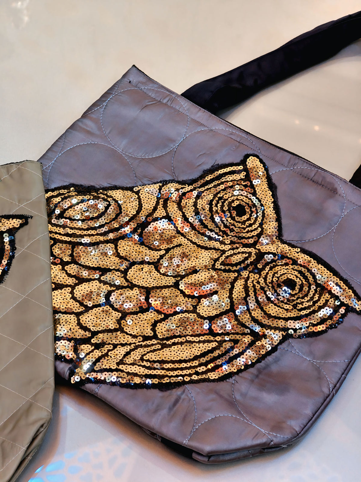 Handbag with a gold fish design on a reflective surface