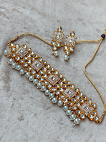 Pearl and gold jewelry set on a textured surface
