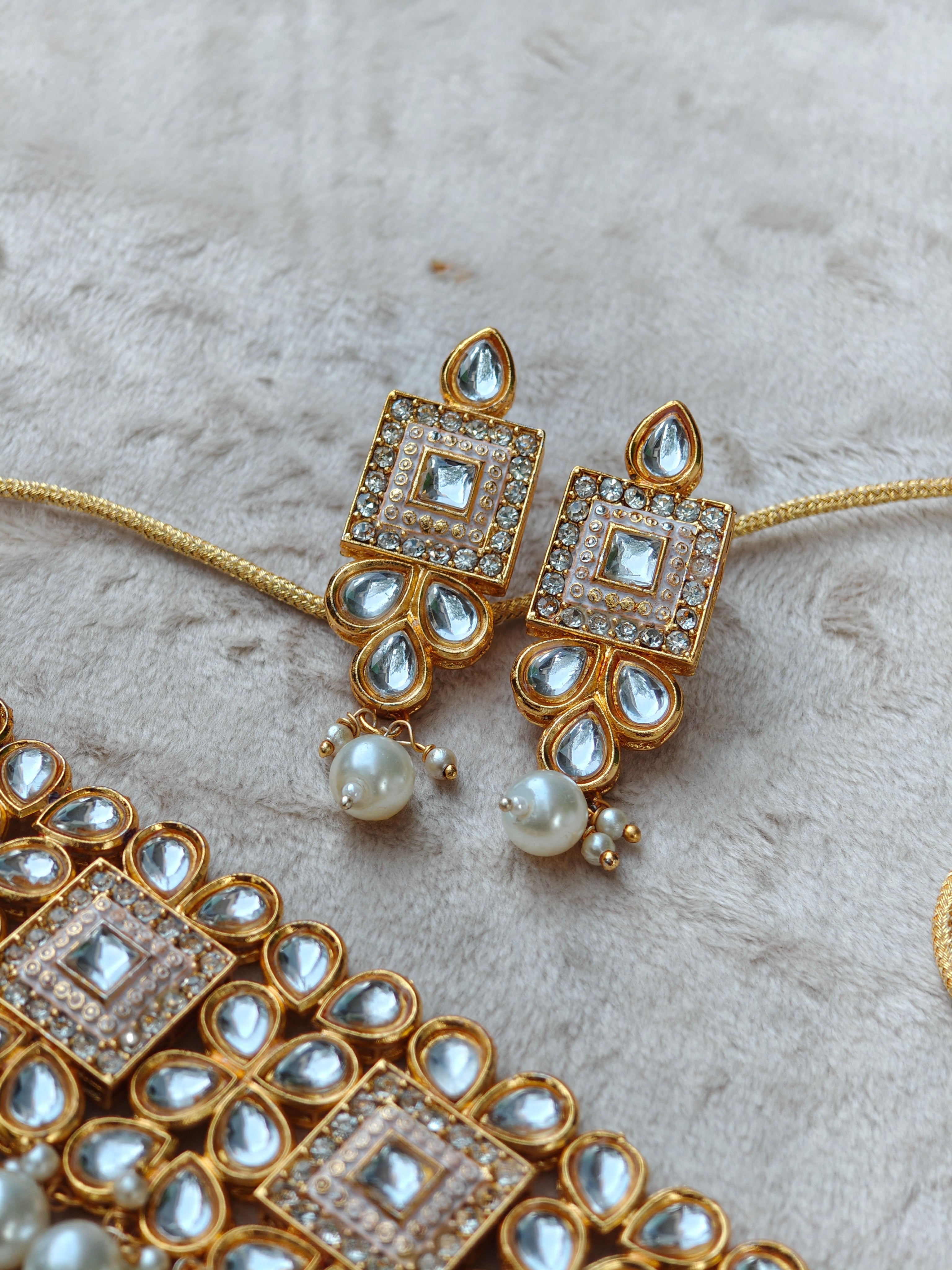 Gold and pearl jewelry set on a textured surface