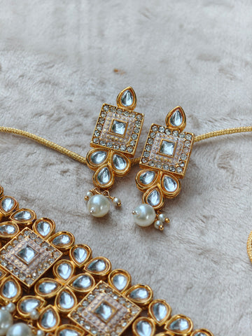 Gold and pearl jewelry set on a textured surface