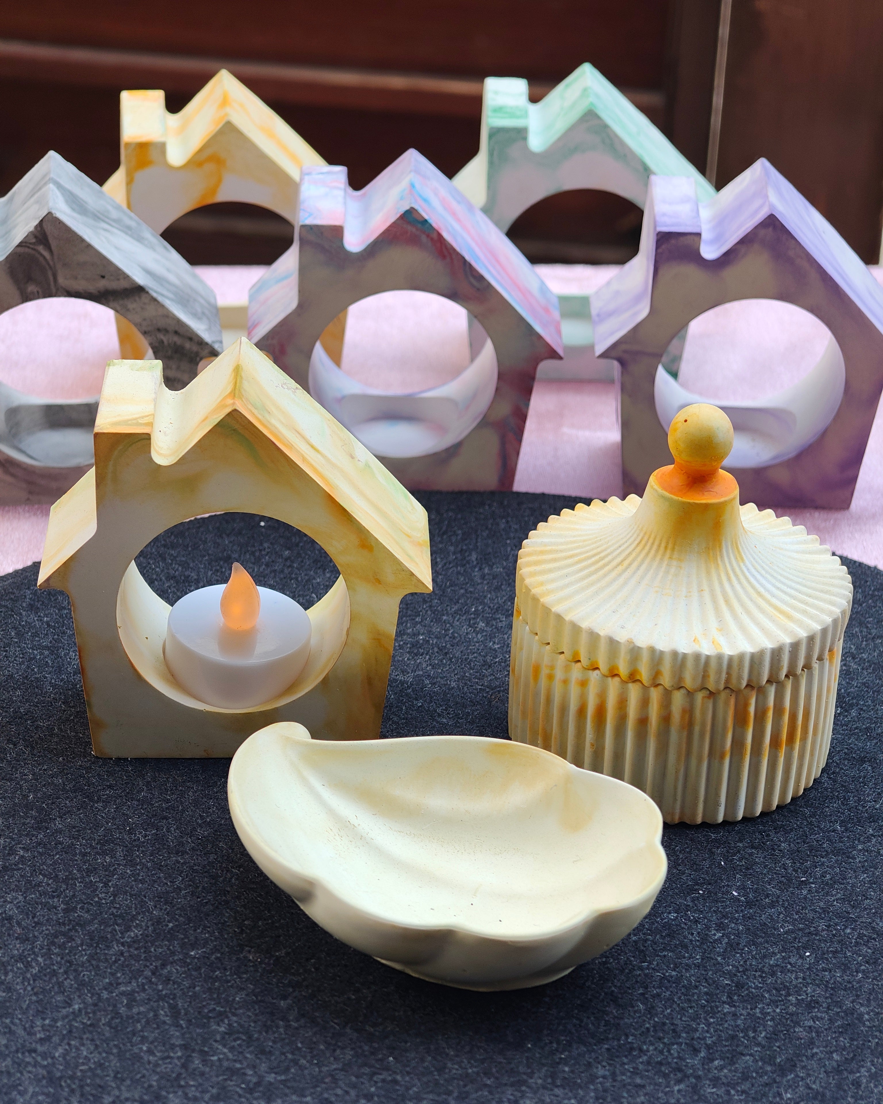 Set of decorative items including a small house, boat, and shell on a dark surface.